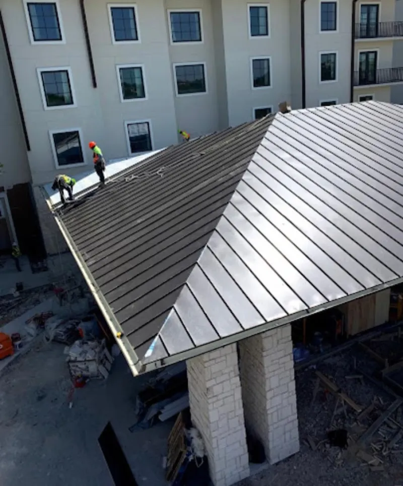 Crew installing standing seam metal roof panels on a commercial project in Williamstown
